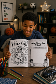 Child holding a coloring book titled 'I Am a King' in a room with books and sports balls.