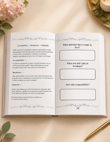 An open book or journal spread laid flat on a warm cream background, with printed reflection prompts on both pages. Pink flowers and green leaves decorate the corners, and a gold pen rests at the lower right. Mental health journal for women