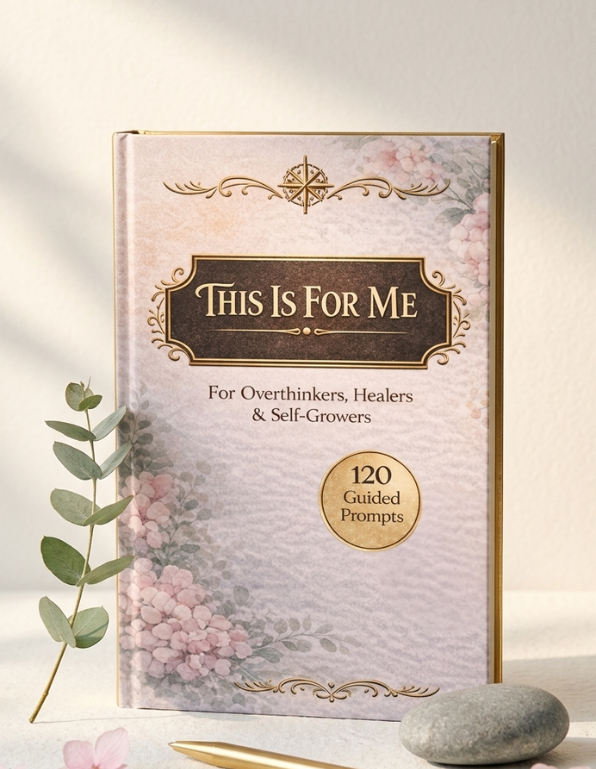 A hardcover book titled 'This Is For Me' with a pale pink floral cover, gold border details, and a gold seal reading '120 Guided Prompts.' It is photographed upright on a light surface with a eucalyptus stem and smooth stone beside it.