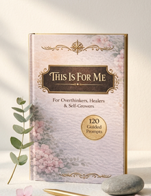 A hardcover book titled 'This Is For Me' with a pale pink floral cover, gold border details, and a gold seal reading '120 Guided Prompts.' It is photographed upright on a light surface with a eucalyptus stem and smooth stone beside it.